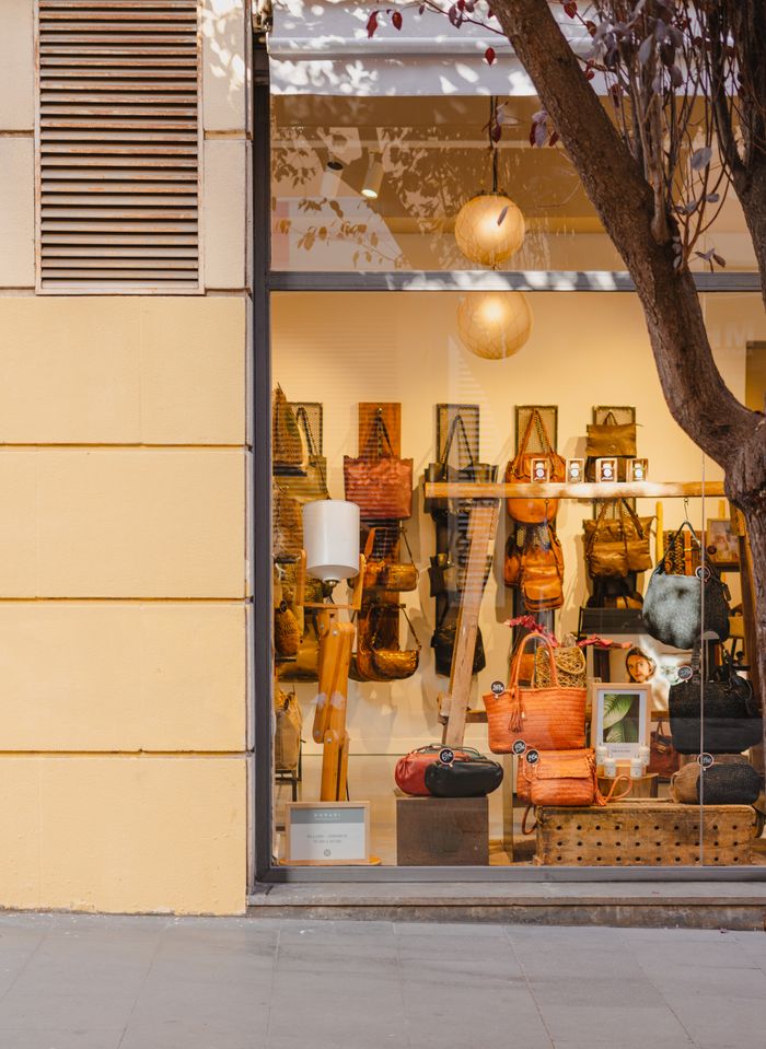 ours-journey Elegant handbag store display in Barcelona, featuring a variety of stylish bags through a large glass window.