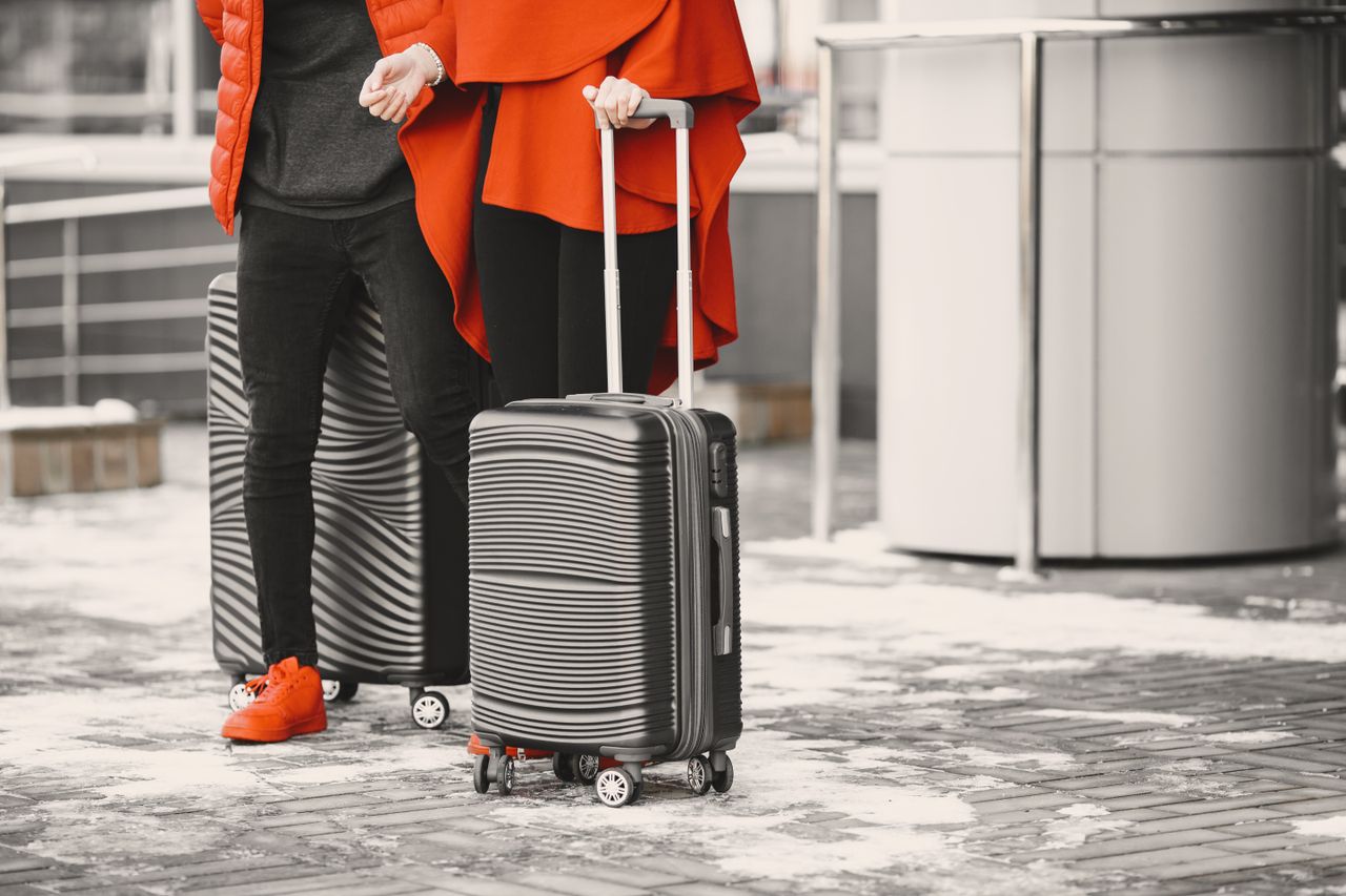 The Art of Drawing Readers In: Your attractive post title goes here A fashionable couple in winter attire with sleek luggage, standing outdoors on a snowy day.