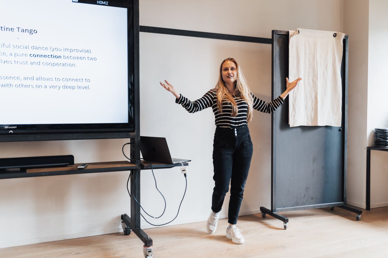 Businesswoman presenting a lecture in an office with a screen display and a laptop.